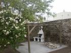 Zahradní krb Beskyd se stolkem v levo s bílou fasádou a udírničkou.